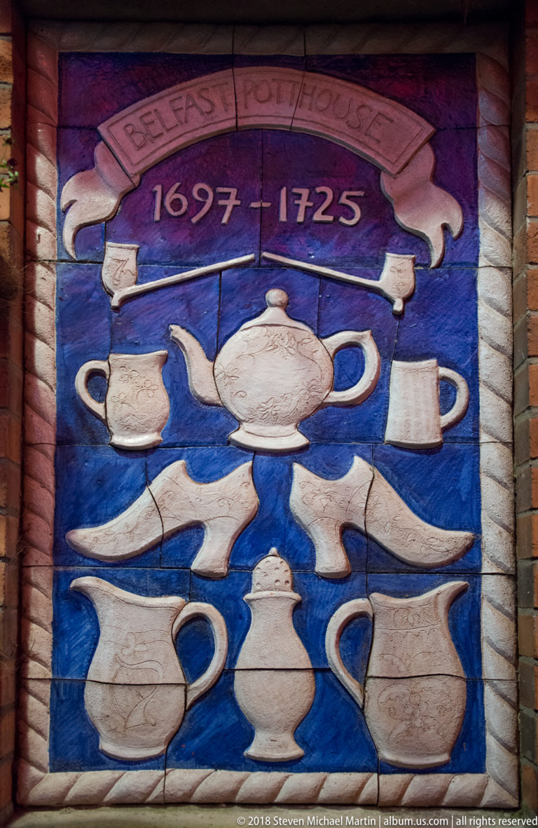 Decorative blue wall panel with white teapots, jugs, cups, and the dates 1697–1725.