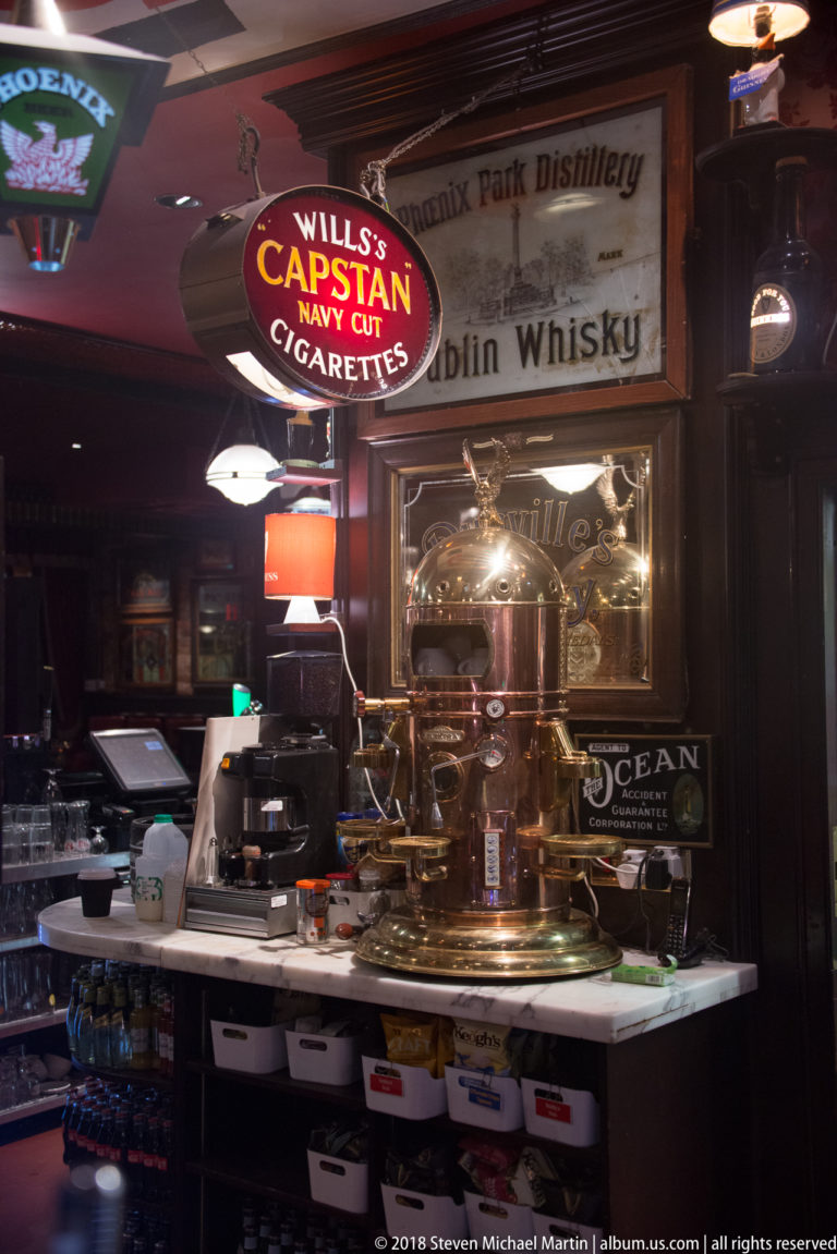Captain Navy Cut Cigarettes sign above a polished brass pub display with old whiskey advertisements behind it.