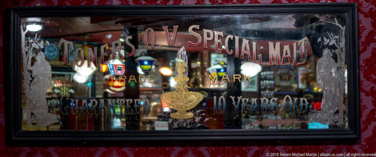 Aged advertising mirror for Connor’s V.O.V. Special Malt with painted lettering and reflections from pub lights.