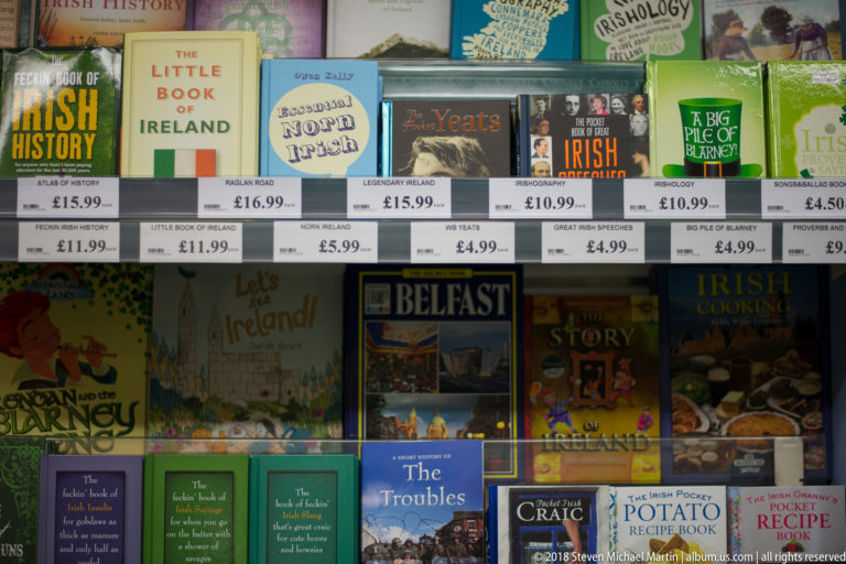 Retail shelf of books on Irish history, folklore, cooking, Yeats, Belfast, and local stories with visible price labels.
