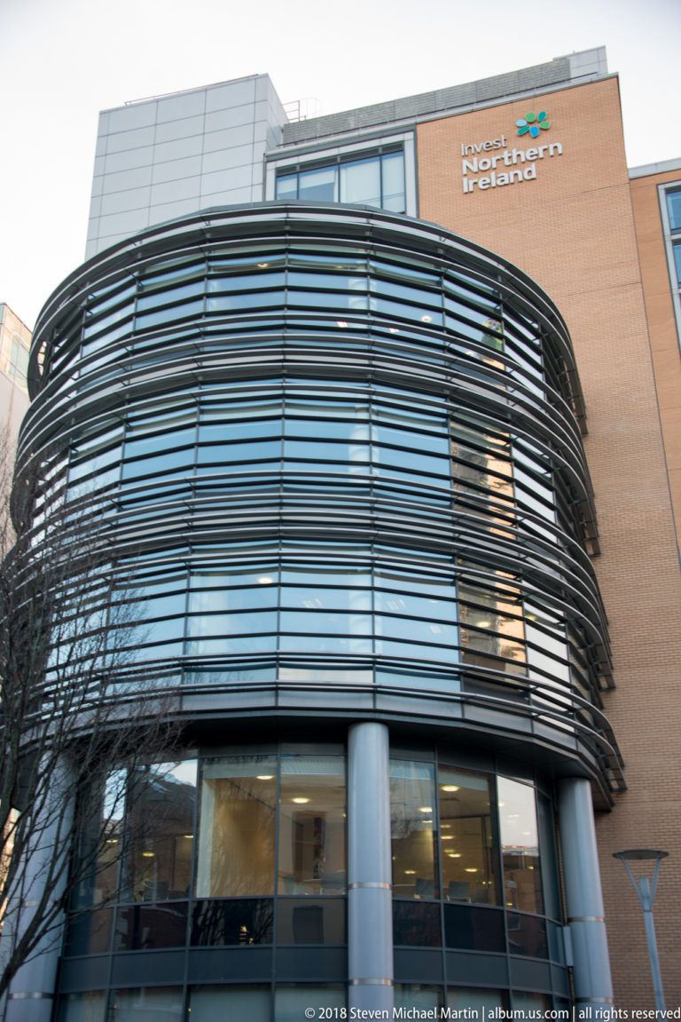 Modern Invest Northern Ireland office with a rounded glass corner wrapped in horizontal metal sun-shading fins.