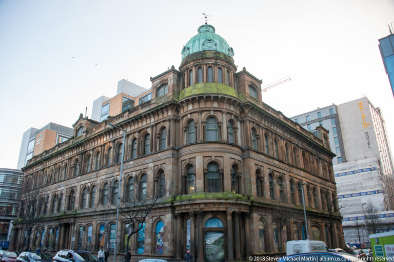 Ornate stone Scottish Provident Institution building on a street corner, topped by a green-patinated dome.