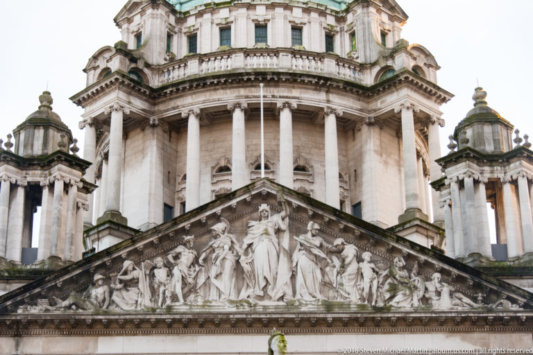 Sculpted triangular pediment on Belfast City Hall beneath the columned drum of the central dome.