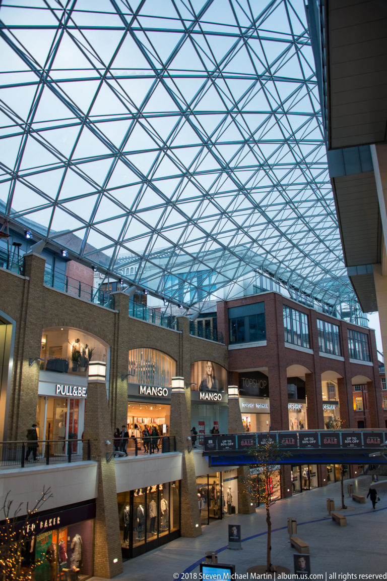 Multi-level Victoria Square shopping centre interior beneath a broad steel-and-glass lattice roof.