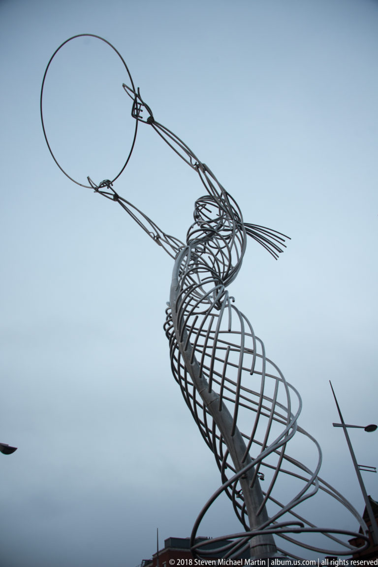 Open-frame metal seahorse sculpture silhouetted against a pale Belfast sky.