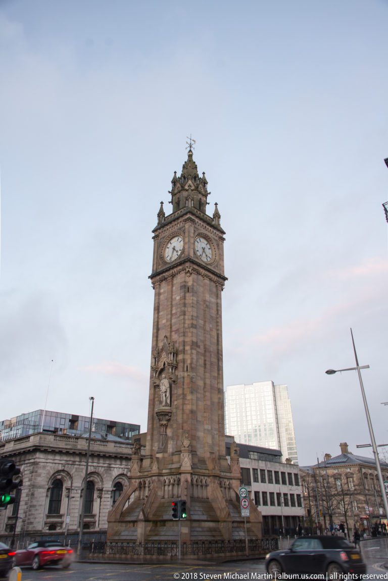 Albert Memorial Clock tower rising above a Belfast street intersection at dusk.