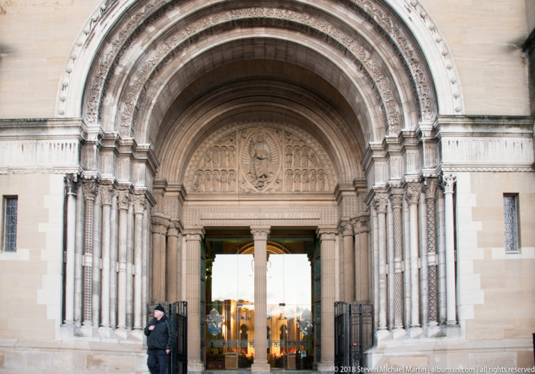 Deeply carved round-arched entrance portal at St Anne's Cathedral, with glass doors open to the interior.