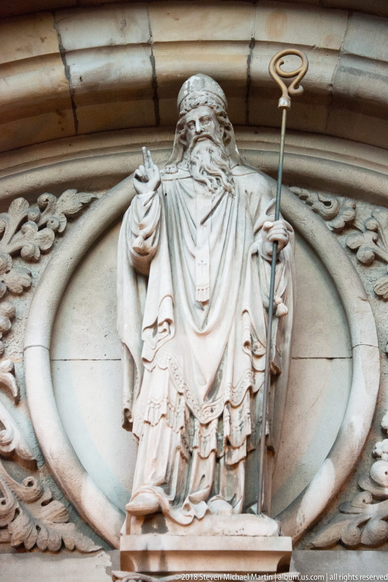 Portland-stone statue of St Patrick as a bearded bishop holding a crozier and raising one hand in blessing above the church entrance.