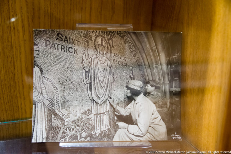 Black-and-white archival photograph of a person working on a large Saint Patrick mosaic labeled 'Apostle of Christ.'