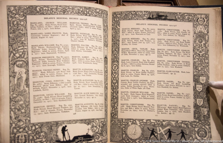Open memorial book with two pages of names arranged in dense columns inside decorative borders.