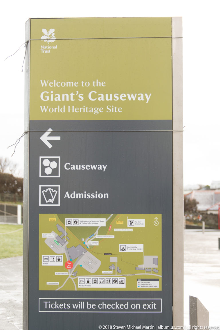 Official Giant’s Causeway World Heritage Site sign with arrows for the Causeway and admission, plus a site map.