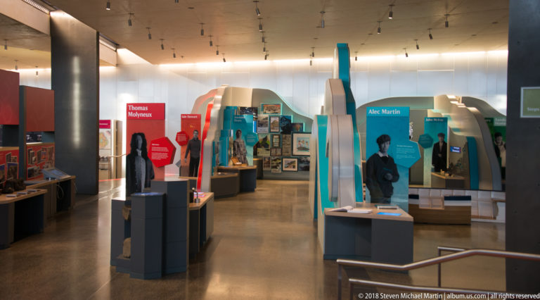 Visitor-centre gallery with colorful interpretive panels, display cases, photographs, and life-size figures.