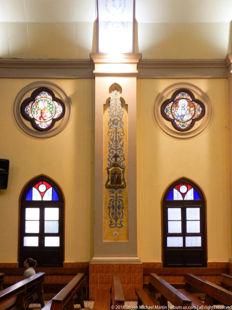 Two oval stained-glass medallions flanking a tall blue-and-gold painted wall panel above dark arched windows.