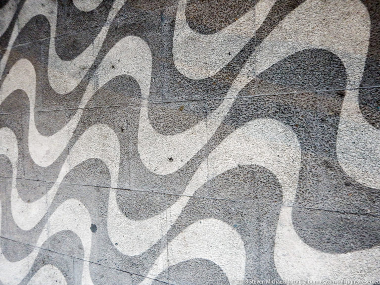 Black-and-white stone pavement arranged in broad repeating wave patterns.