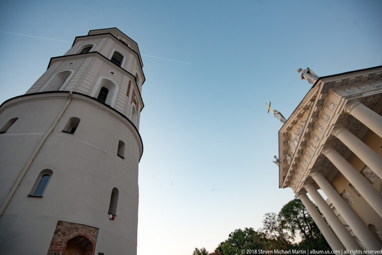 Low-angle view of Vilnius Cathedral Bell Tower beside the cathedral’s sculpted classical pediment and columns.