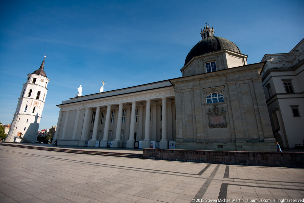 Vilnius Cathedral’s pale columned exterior and low dome beside the separate white bell tower on Cathedral Square.