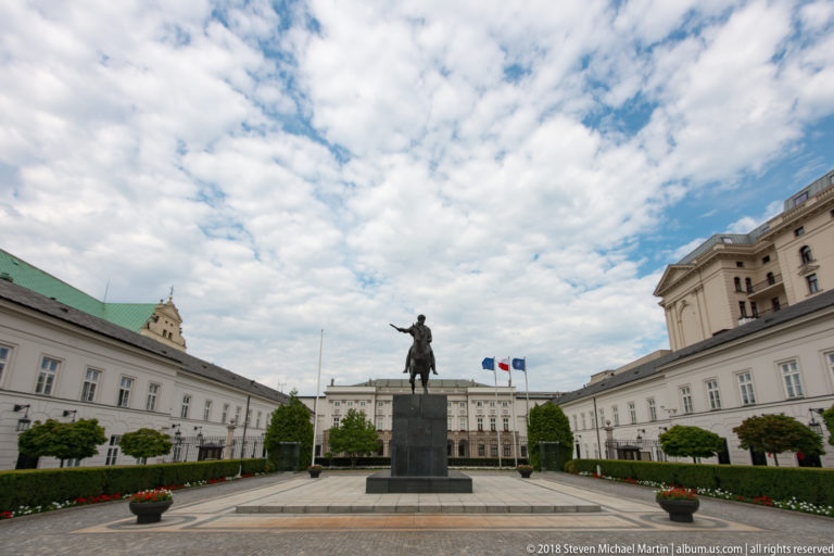 Equestrian Prince Józef Poniatowski Monument centered in the Presidential Palace courtyard with palace buildings and clipped trees.