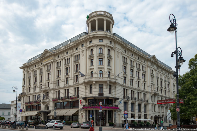 Historic Hotel Bristol on a rounded street corner with cream facade, tall windows, rooftop pavilion, and ground-floor awnings.