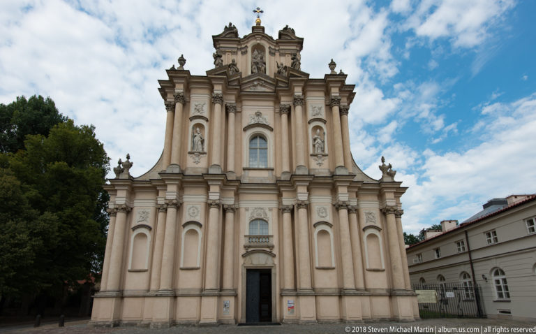 Baroque church facade with sculpted niches, paired pilasters, deep cornices, and a shaped upper gable.