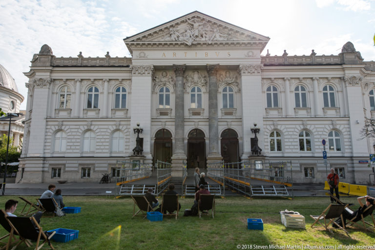 Zachęta National Gallery of Art facade with ARTIBUS inscription, ornate pediment, and temporary seating on the lawn.