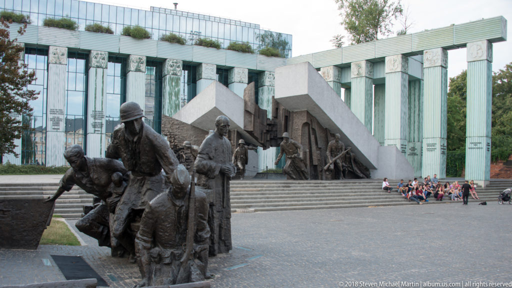 Bronze figures of the Warsaw Uprising Monument stand before steps and the modern Supreme Court complex.
