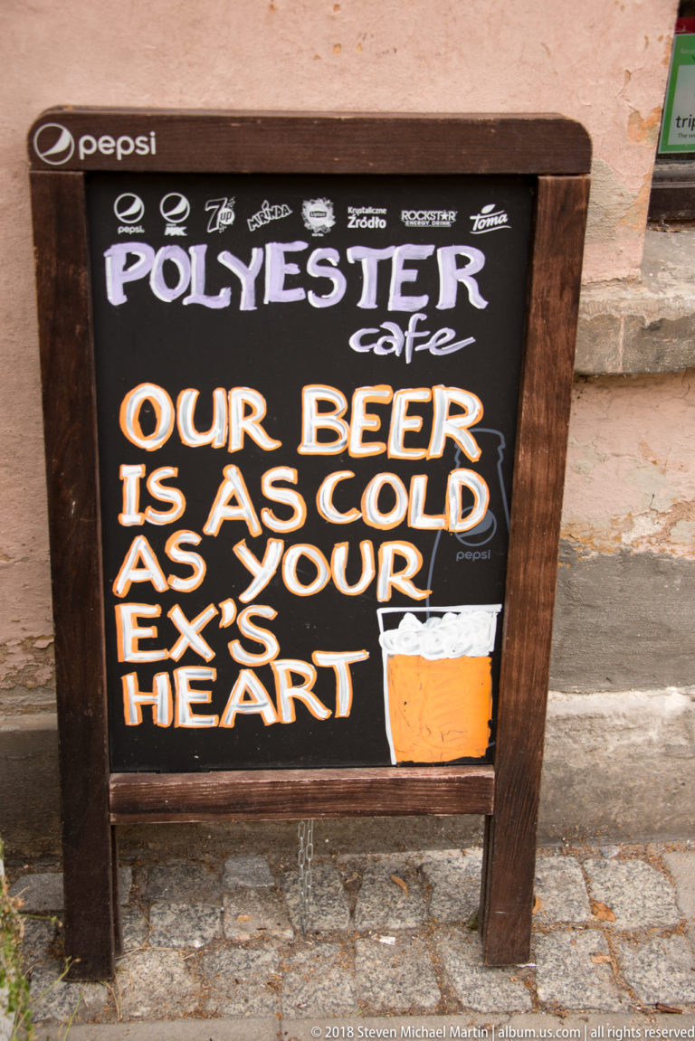Pollyester Café chalkboard reading Our beer is as cold as your ex's heart beside a painted beer glass.