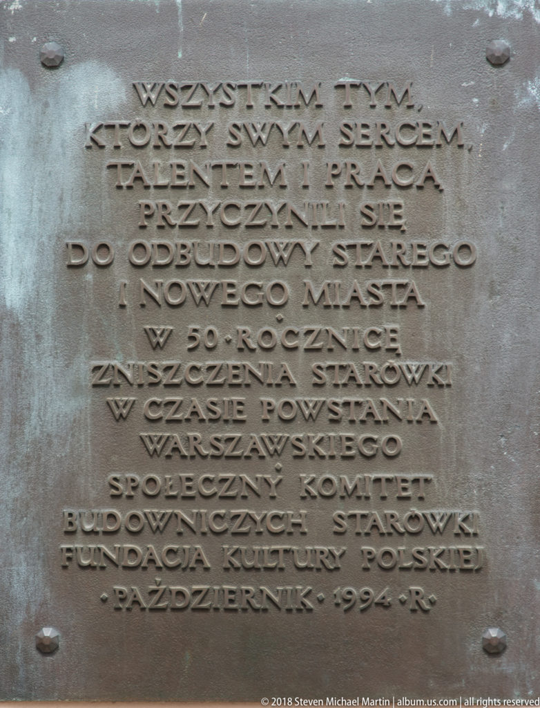 Bronze Polish-language plaque commemorating the reconstruction of Warsaw's Old and New Towns after World War II.