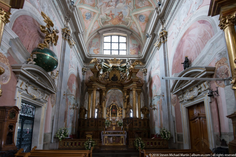 Ornate side altar in St. Anne's Church with gilded sculpture, flowers, painted walls, and a green spherical ornament.