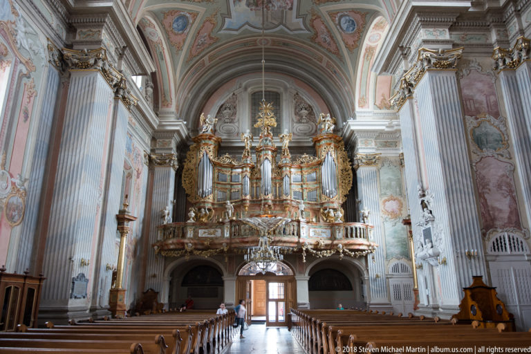 Large gilded pipe organ above the entrance of St. Anne's Church beneath a painted Baroque vault.