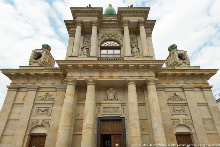 Carmelite Church facade with paired columns, sculpted niches, relief panels, and green-capped rooftop elements.