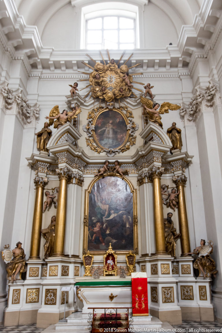 Large gilded side altar with two devotional paintings, sculpted angels, columns, and decorative pediments.