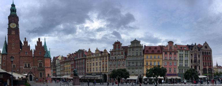 Old Town Hall and colorful Rynek townhouses beneath dark storm clouds in central Wrocław.