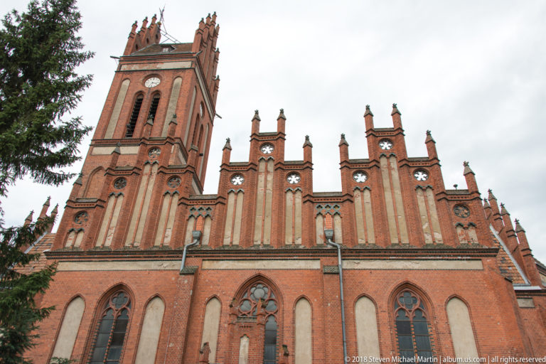Close view of red-brick stepped gables, pinnacles, pointed windows, and tracery on the Church of Saints Peter and Paul.