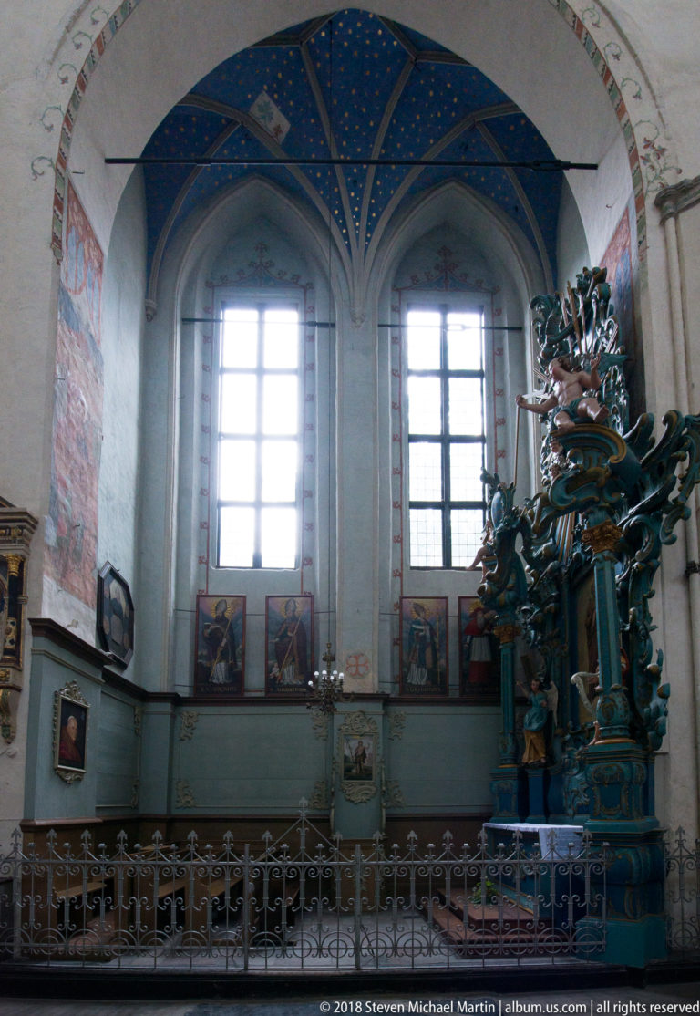 Side altar with dense Baroque carving beneath blue-painted Gothic vaulting and tall windows inside St Mary’s Church, Toruń.