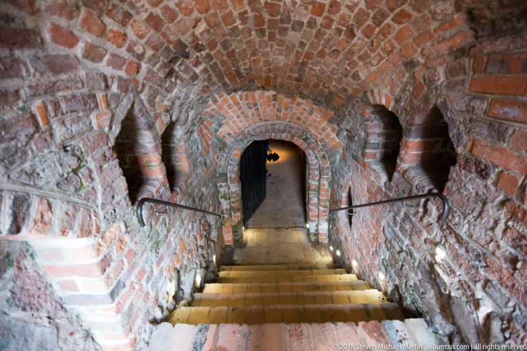 Steep stairs descending through a narrow brick-vaulted corridor in the Teutonic Castle ruins.