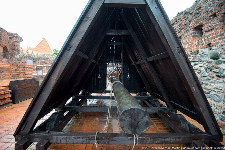 Long wooden beam and mechanism inside a steep A-frame siege-engine reconstruction at the castle.