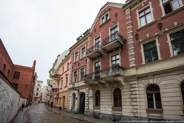 Historic red-brick and stucco townhouses lining a narrow cobbled street in Toruń Old Town.