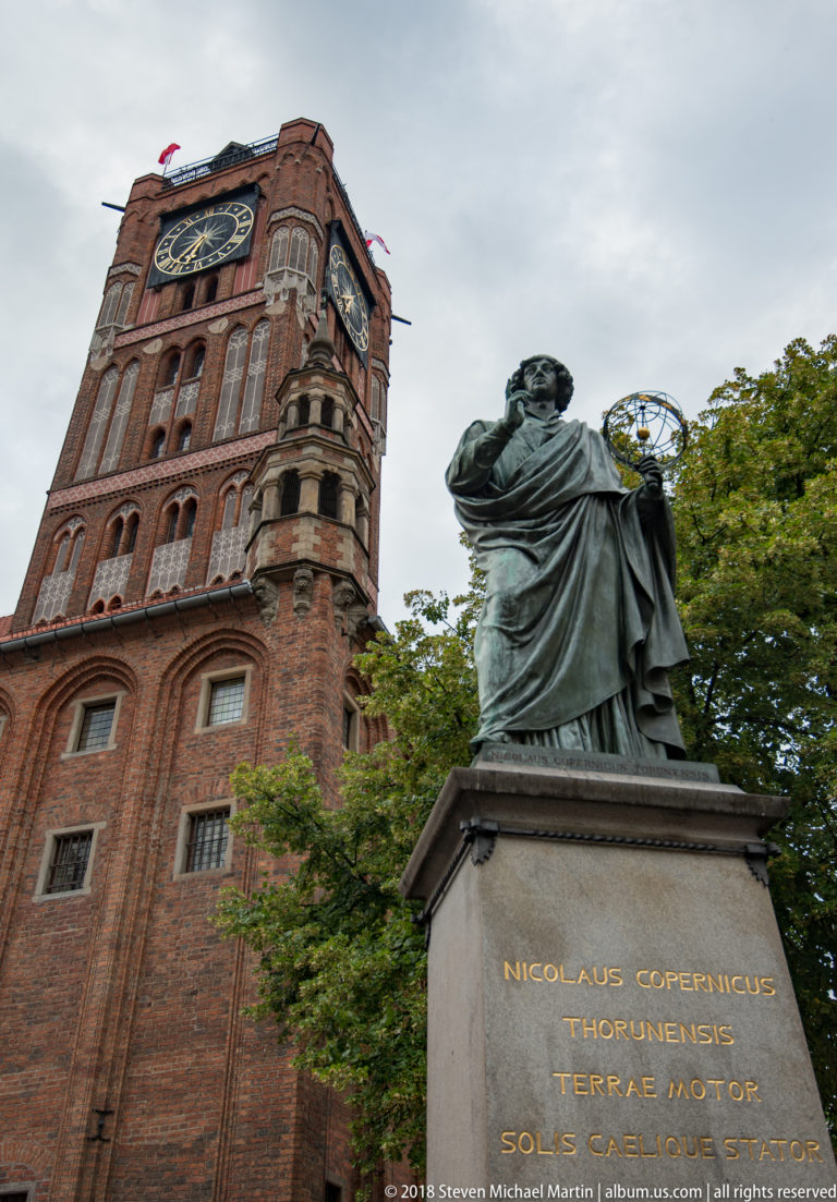 Bronze Nicolaus Copernicus statue holding an armillary sphere before Toruń Old Town Hall.