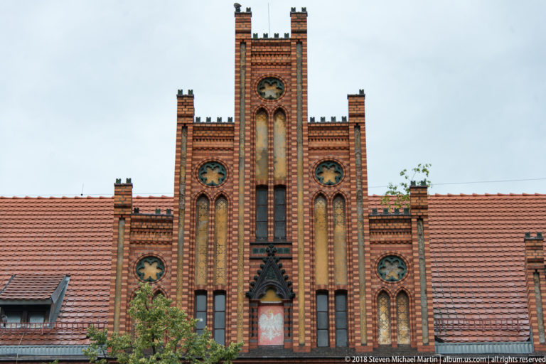 Symmetrical red-brick stepped-gable façade with blind arches and circular decorative openings in Toruń.