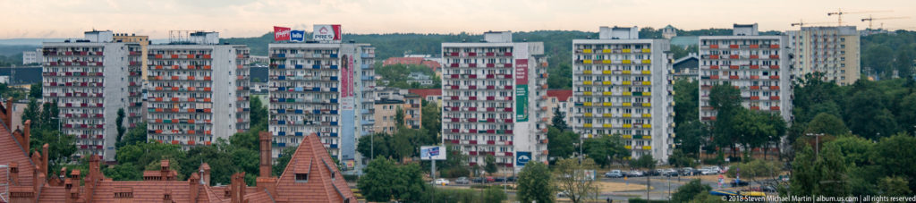 Modern apartment towers rising behind red-brick historic rooftops and pinnacles in Toruń.
