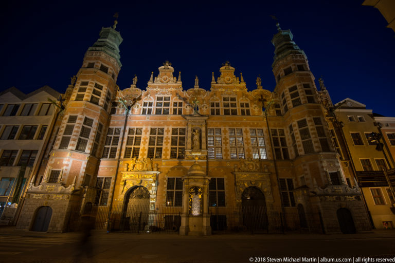 Illuminated Great Armoury with ornate red-brick façade, gilded sculpture, decorative gables, large windows, and corner towers.