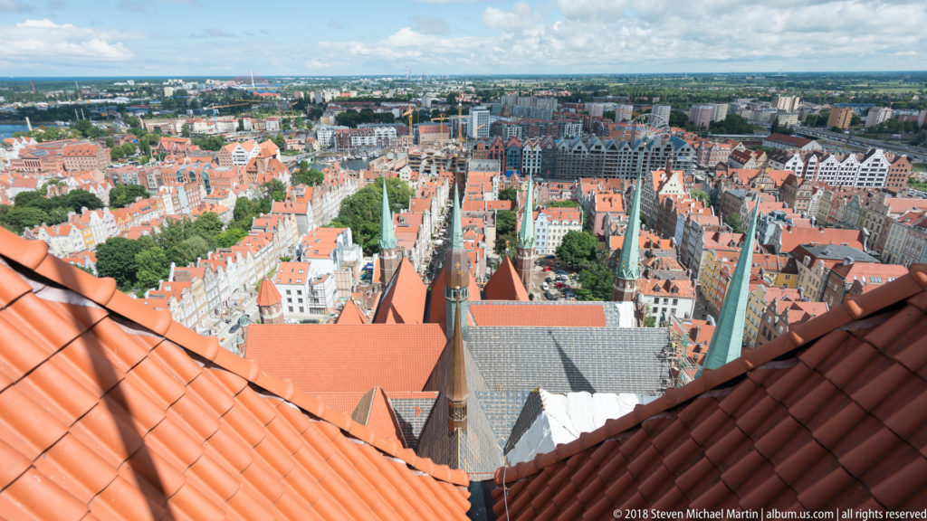 High view from St. Mary’s Basilica tower over red roofs, narrow streets and gabled buildings of central Gdańsk.