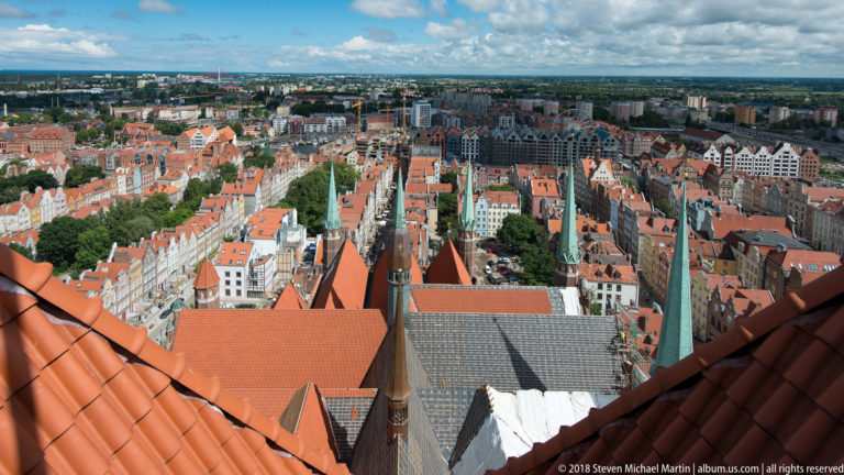 Elevated panorama over red-roofed historic buildings and narrow streets from St. Mary’s Basilica tower.