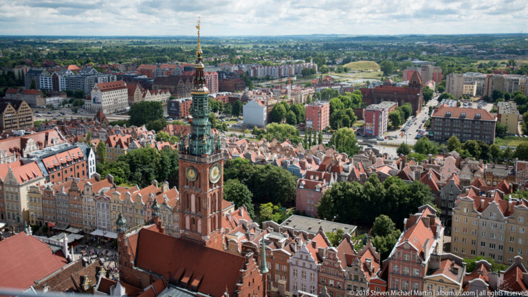 Main Town Hall tower rising above red roofs and colorful historic buildings in central Gdańsk.