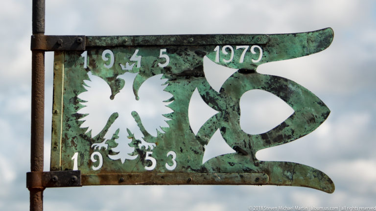 Green-patinated metal vane with white Polish eagle and painted dates 1945, 1953 and 1979.