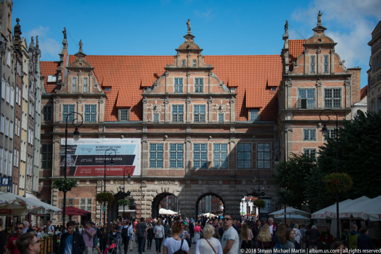 Green Gate with ornate brick gables and arched passages above crowds at the end of Gdańsk’s Long Market.