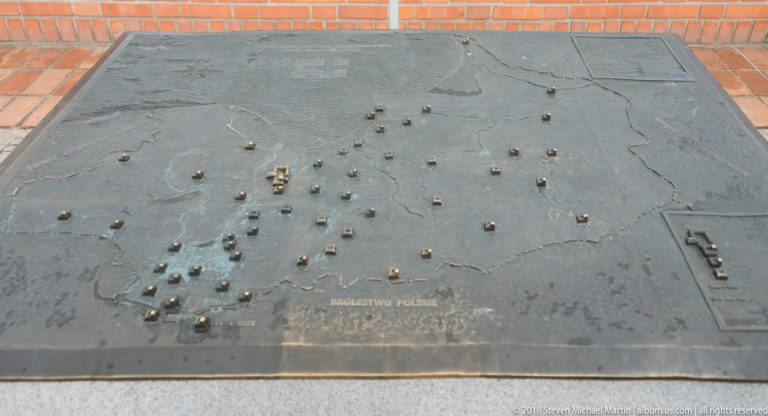 Dark metal tactile site map with raised miniature buildings, engraved terrain, and the label “MALBORK.”