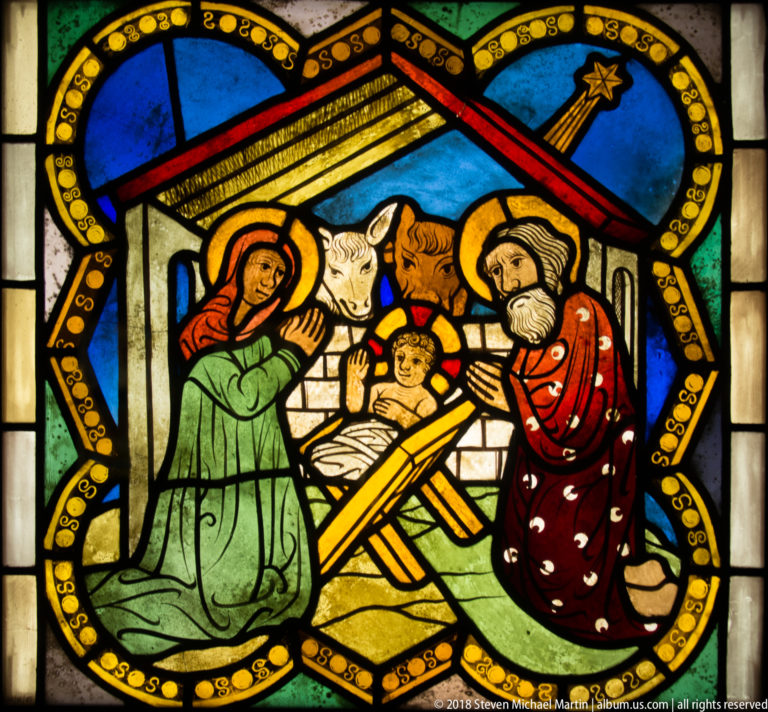 Nativity scene with Mary, Joseph, infant Christ in a manger, ox and ass, and a star above.