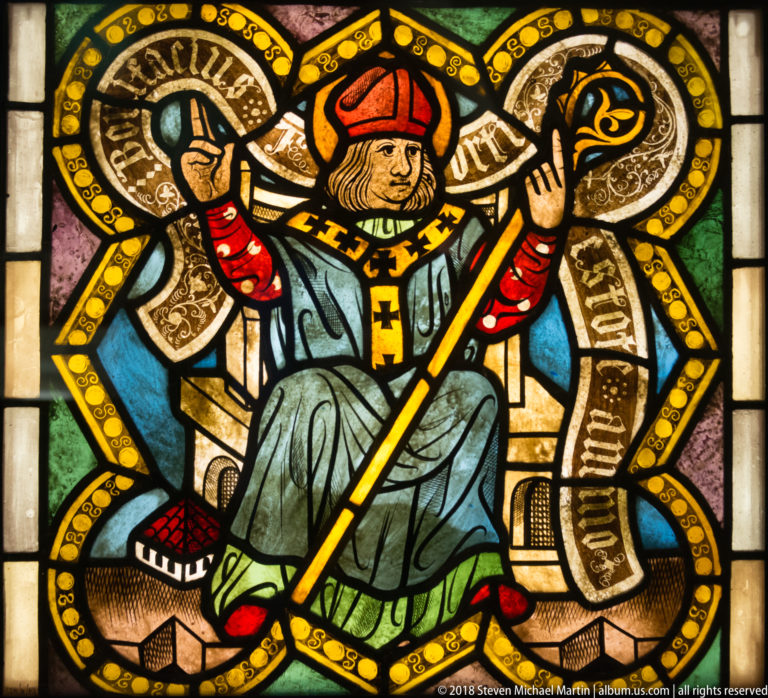 Saint James the Lesser seated with staff or club, halo, and surrounding inscription.
