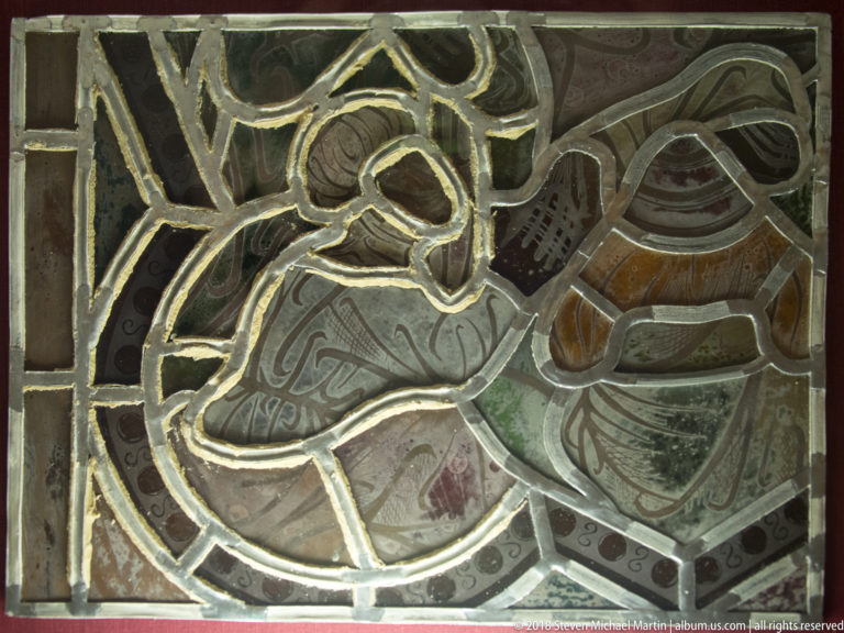Completed figural stained-glass assembly with painted pieces held together by a dense network of lead cames.
